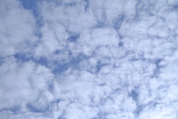 White fluffy clouds against blue sky in bright day for background texture 