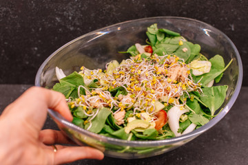 man´s hand holding a glass bowl of Soy sprouts salad.