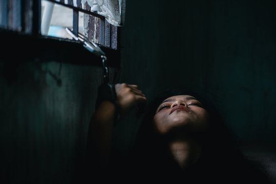 Asian woman get scared human trafficking and trying escape from the room but detainees woman stick to the handcuffs and detain in dirty room. She was kidnapped or abducted, typically to obtain ransom.