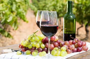 glass of red wine and ripe grapes on table