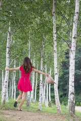 Woman in hat holding birch in forest. in summer