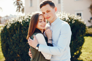 handsome young guy in a blue shirt standing in a sunny summer park along with her cute girl in a white shirt