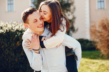 Fototapeta premium handsome young guy in a blue shirt standing in a sunny summer park along with her cute girl in a white shirt