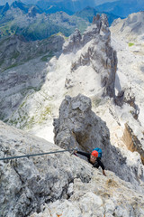 attractive blonde female climber on a steep Via Ferrata in the Italian Dolomites