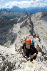 attractive blonde female climber on a steep Via Ferrata in the Italian Dolomites