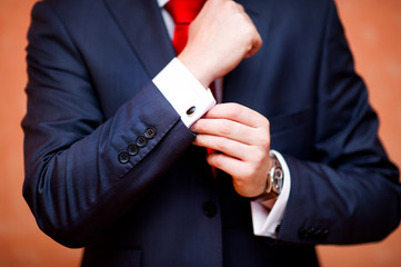 the groom defiantly straightens the cufflink on the shirt, the sleeve of which peeps from under the jacket, close-up