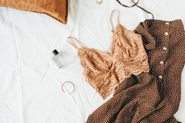 Fashion trendy underwear composition. Bra, perfume, evening dress on white linen background. Flat lay, top view beauty blog / social media minimal concept.