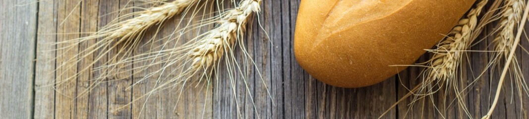 banner of Freshly baguettes baked bread and wheat spikes on wooden background
