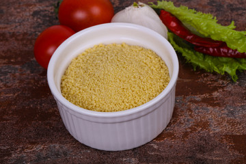 Raw couscous in the bowl served salad leaves, tomato and pepper