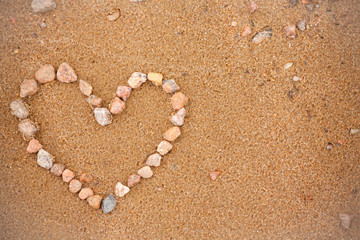 Fototapeta na wymiar Heart on the beach. Heart of stones on a golden beach. Symbol of love, photography background or blank for greeting card. Valentines day. Concept with heart on the theme of holidays and travel. 
