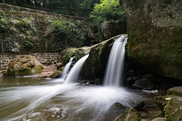 Fototapeta premium idyllic small waterfall in lush green forest landscape