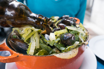 pouring beer over traditional mussel and french fries dish called 