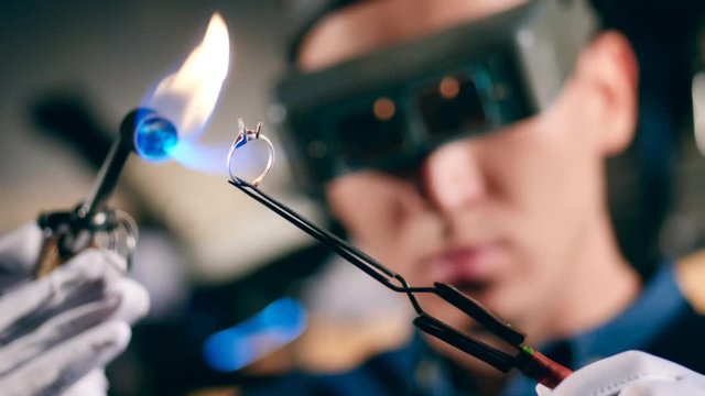 A jeweller uses welding machine while working with a ring.