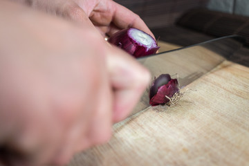 woman cutting a red onion isolated on wood