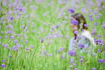 Lady in beautiful garden with purple flowers. Young woman in nature park with beautiful blossom.