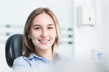 Portrait of an attractive smiling girl blonde in a dental chair. Happy customer dental cabinet