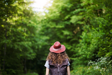 Rear view of young tourist woman traveller with backpack walking in nature.