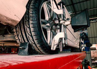 Tire clamped with lazer aligner undergoing auto wheel alignment in modern garage