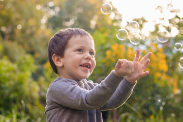 A boy on the street catches soap bubbles. Happy childhood. Children's games.