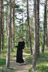 Fototapeta na wymiar Woman in black clothes is standing in the forest