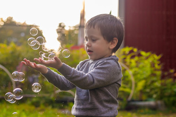 A boy on the street catches soap bubbles. Happy childhood. Children's games.