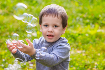 A boy on the street catches soap bubbles. Happy childhood. Children's games.