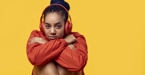 African teenage girl with dreadlocks in red windbreaker listening music