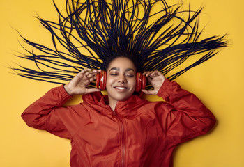 African teenage girl with dreadlocks in red windbreaker listening music