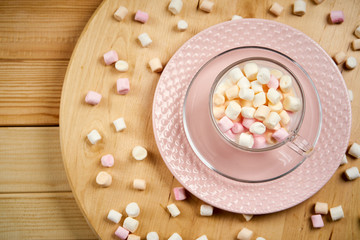 Obraz na płótnie Canvas Cup with hot milk and colorful marshmallows on wooden table