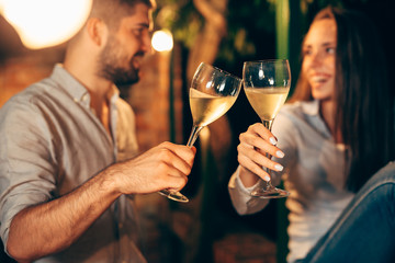romantic couple drinking wine on backyard decking . evening scene