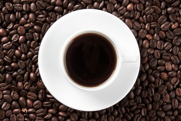 Cup of coffee surrounded by coffee beans