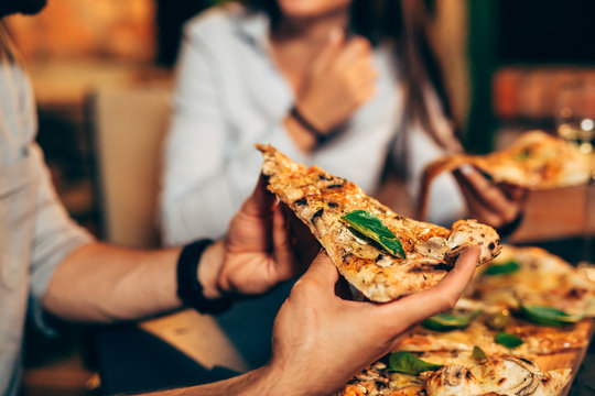 close up of people eating pizza.