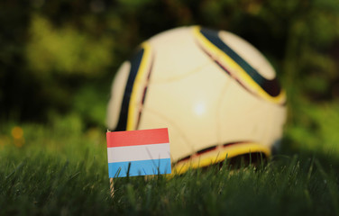 Netherlands national flag on wooden stick stabbed in grass. World Championship 2022. Euro 2020. Flag of Holland and blurred background - Powered by Adobe