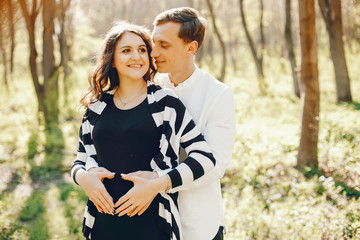 bright and happy pregnant woman walking in the park with her husband