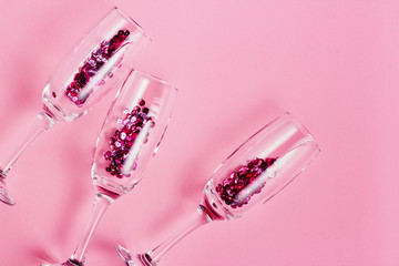 Christmas and New Year or holiday festive card. Champagne glasses and sparkles over pink background