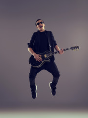 Naklejka premium Fifteen years old guitarist with a black electric guitar. Teenage musician holds guitar