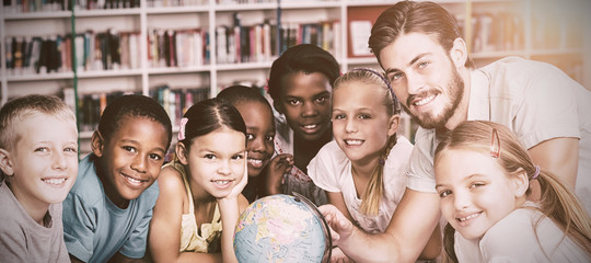 Pupils and teacher looking at globe in library 