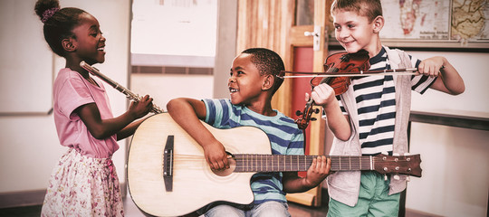 Naklejka premium Children playing musical instruments in classroom