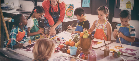 Teacher assisting schoolkids in drawing class