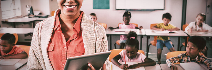 Teacher posing in front of class with tablet pc