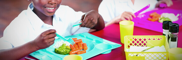 Obraz na płótnie Canvas Boy and girl in school uniforms having lunch in school cafeteria