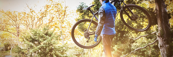 Mountain biker carrying bicycle looking at nature