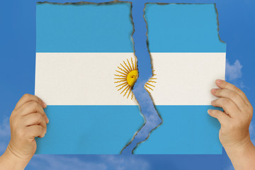 woman holds in both hands against a blue sky torn in two cardboard with seared edges depicting the...