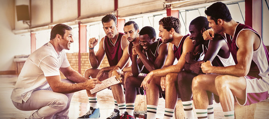 Fototapeta na wymiar Coach explaining game plan to basketball players