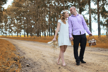 Just married lovers walking in a field in autumn day