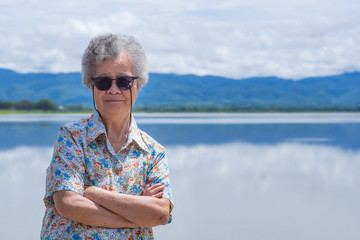 Fototapeta premium Senior woman standing and smile at side the lake