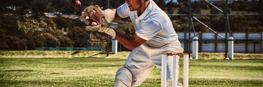 Wicketkeeper catching cricket ball behind stumps