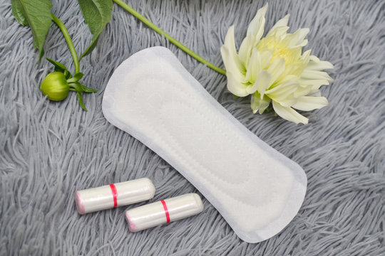 Daily panty liners on a background of flowers close-up. Discrete pads or pads for women. Intimate hygiene. Protection of feminine hygiene. Women Health. Critical days.