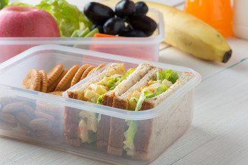 Lunch box set of Egg salad with sandwich slices in box and almond, peanut butter cracker with fruits and vegetables in boxs. Healthy and Diet food.