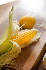  Semi-peeled corn and lemon on a wooden board